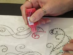 a woman is using an adhesiver to make a stencil on a piece of paper