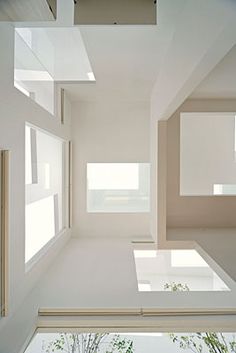 an empty room with windows and plants in the center, on top of white walls