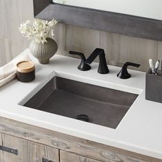 a bathroom sink sitting under a mirror next to a wooden cabinet and white counter top