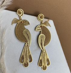 These beautiful parrot-shaped earrings are handmade in sterling silver filigree and plated with 24k gold. With a detailed and elegant design inspired by the exotic beauty of parrots, these long earrings are a unique piece of artisan jewelry. Perfect for any special occasion. Grana is a new jewelry brand in Filigree, traditional and ancestral technique. We like to tell stories through each piece, our intention is to create objects linked to the value of the feminine figure and leave a mark on eac Elegant Drop Earrings With Bird Design, Elegant Bird Design Drop Earrings, Gold Earrings With Bird Shape, Elegant Gold Jewelry With Bird Design, Unique Gold Earrings With Intricate Design, Sterling Silver Filigree, Jewelry Brand, Silver Filigree, New Jewelry