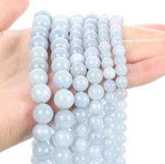 a hand holding several light blue beads in it's palm