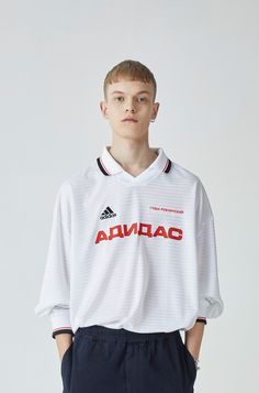 a young man is standing in front of a white background and wearing an adidas shirt