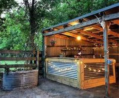 an outdoor bar in the middle of a wooded area with lots of lights on it