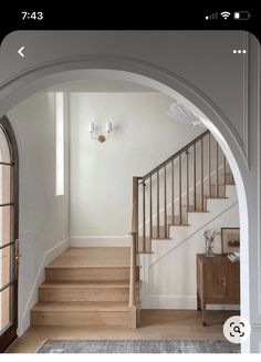 an arch leading up to the second floor in a home with wood floors and white walls