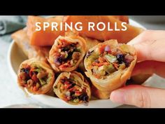 a person is holding some food on a plate with the words spring rolls in front of them