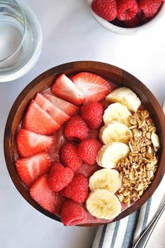 a wooden bowl filled with fruit and granola