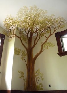 a tree painted on the side of a wall in a room with windows and blinds