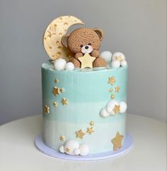 a teddy bear sitting on top of a blue and white cake with stars around it