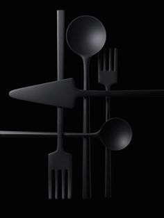 spoons, forks and knives are arranged on a black background