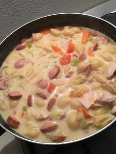 a pot filled with pasta and ham on top of a stove