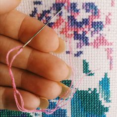 the needle is hooked up to thread on the cross - stitch pattern with pink yarn