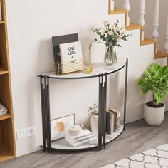 a corner table with flowers and books on it next to a stair case in a living room