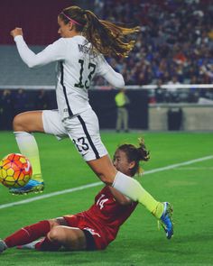 two women are playing soccer on the field