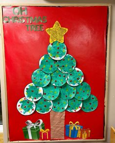 a christmas tree made out of paper plates on top of a bulletin board with presents under it