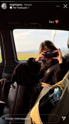 a woman sitting in the back seat of a car holding a cell phone up to her face