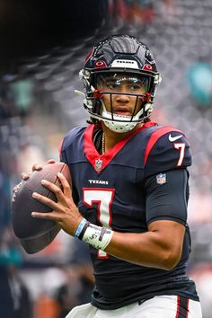 a close up of a football player holding a ball in his hand and wearing a helmet