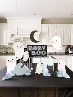 a black table topped with paper cutouts and ghost decorations next to a kitchen counter