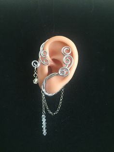 a fake ear with chains attached to it on a black surface, and an ear chain hanging from the side