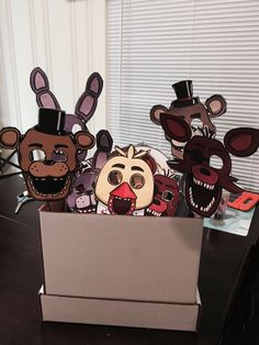 three paper animal masks in a box on a table