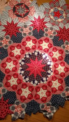 a red, white and blue quilt is laying on the floor with it's center star design