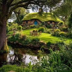 a green hobbot house surrounded by trees and water