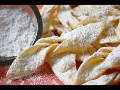 some powdered sugar on top of an orange plate with apples in the back ground