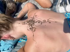 a man with a tattoo on his back laying in the sand