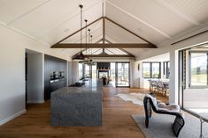 an open kitchen and living room with wood flooring, white walls and ceiling beams