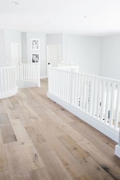 an empty room with white railings and wood flooring in the center is shown