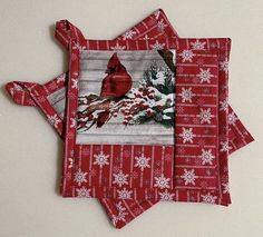 three red placemats with white snowflakes on them and a cardinal design