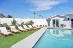 an empty pool with lawn chairs next to it and a white house in the background