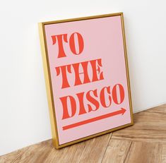 a pink poster with the words to the disco on it sitting on a wooden floor