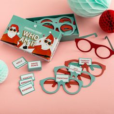 some paper cut outs are sitting on a pink surface next to glasses and other items