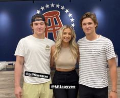 two men and a woman posing for a photo in front of a sign that says,