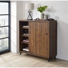 a wooden cabinet with shoes on it in front of a window overlooking the cityscape