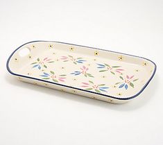 a white tray with blue trim and floral designs on the bottom, sitting on a table