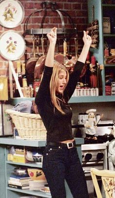 an image of a woman in the kitchen raising her arms up and smiling at someone else