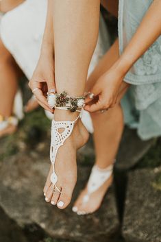 the bride is tying her wedding shoes with white lace and flowers on their ankles as she walks down the aisle