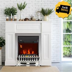 a white fireplace with a fire in it and plants on the mantle next to it