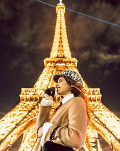 a woman standing in front of the eiffel tower with her cell phone up to her ear