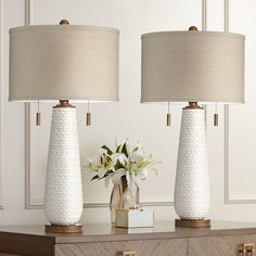 two white vases sitting on top of a table next to each other with flowers in them