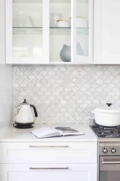 a kitchen with white cabinets and stainless steel stove top oven, tea kettle on the burner