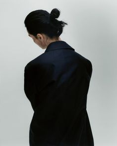 a woman standing in front of a white wall with her back turned to the camera