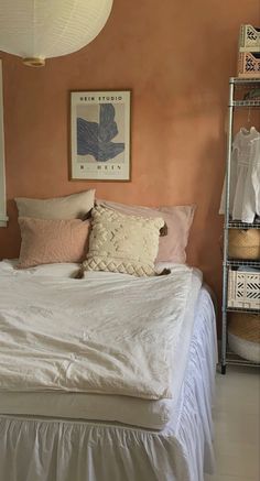 a white bed sitting in a bedroom next to a wall with pictures on the walls