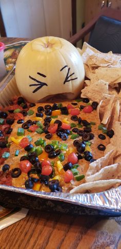 a cat face made out of tortilla chips on a tray next to a pumpkin