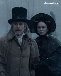 an older man and young woman standing next to each other in the snow wearing hats