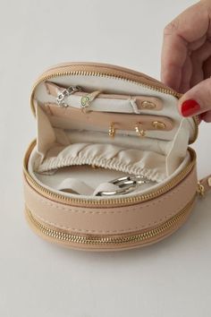 a woman's hand is opening the inside of a small case filled with jewelry