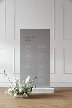 a bouquet of white flowers sitting on top of a wooden floor next to a sheet of paper