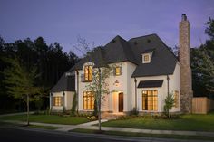 a house is shown at night with the lights on and windows lit up in front