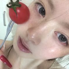 a woman with a tomato on her nose holding a pair of scissors in front of her face